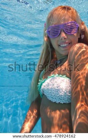 Beautiful smiling blonde girl under the water surface