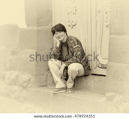 Young woman sitting on the steps of the house in the ancient city of Cusco in Sacred valley of the Incas, Peru (stylized retro)