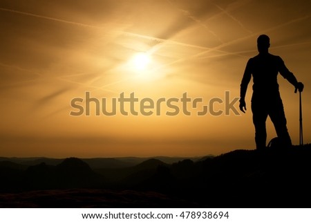 Tourist with poles in hands stand on rock watching  for next step. Sunny spring daybreak in mountains.Vignetting effect.. 