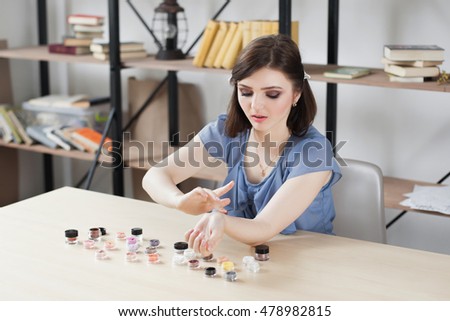 Woman trying eyeshadow colours on her hand. Make-up artist testing colors of decorative cosmetics. Beauty blogger doing swatches