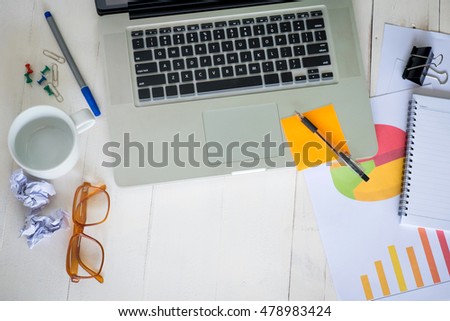 Notebook and pen Business workplace with laptop on the wooden table.with reflection from windows.