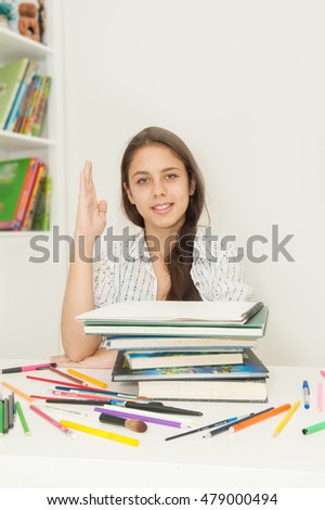 Girl schoolgirl in glasses sits at a desk and textbooks