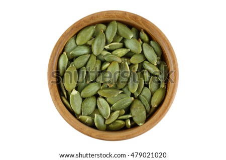 Top view of roasted pumpkin seeds in wooden bowl. Dry Pepita after shelling isolated on white background.
