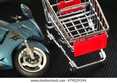 Shopping cart put beside the old and dirty motorcycle plastic model represent the motorcycle maintenance and motorcycle business background concept related idea.