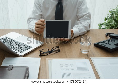 Professional corporate businessman working at office desk and showing a digital tablet
