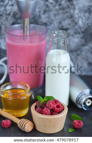 Berry smoothie for breakfast with honey and raspberry on a black background.