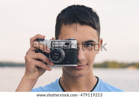 Cute boy teenager with vintage rangefinder camera. Close-up Photo.