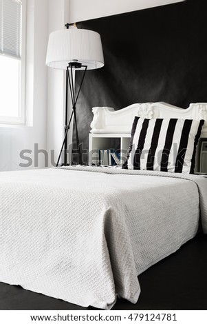 Black and white ascetic style bedroom with large bed and floor lamp