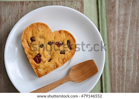 Top view of chocolate chip cookies in the shape of heart on white plate, with wooden background. (Concept about love and relationship)