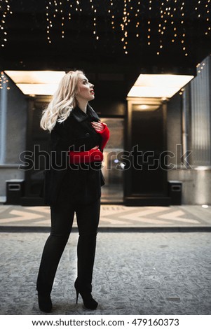 Creative young woman in a black coat walking down the street near the hotel