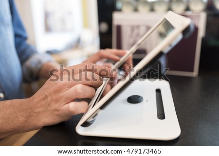 In a restaurant the waiter prepares the bill on computer POS tablet pc. The waiter takes the order on digital tablet Royalty-Free Stock Photo #479173465