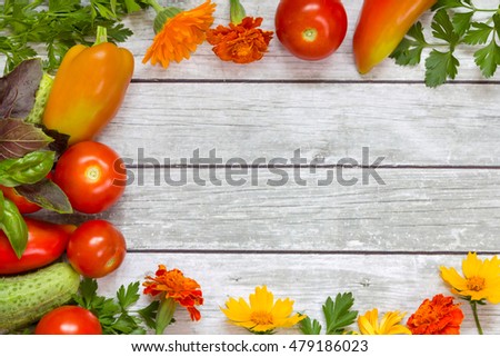Vegetables, parsley and basil, flowers on wooden background.