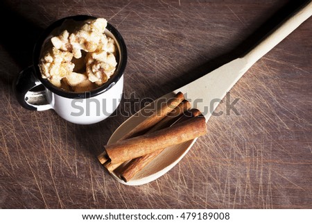 Top view of gourmet cinnamon popcorn inside a rustic white cup with wooden spoon over a  wood cutting board background.