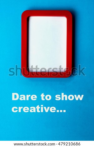The red plastic picture frame on the blue wall with message "Dare to show creative"