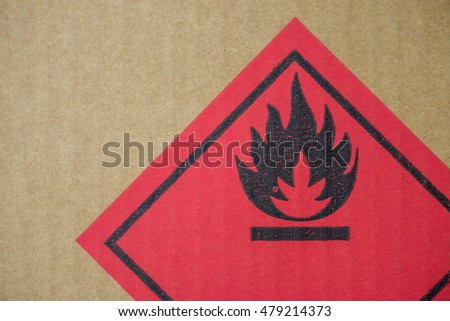 Close-up detail of a fire hazard warning symbol on a cardboard cargo box containing chemicals.