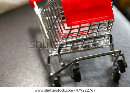 Miniature model of shopping cart trolley put on dark background scene represent the shopping and retail business background concept related idea.
