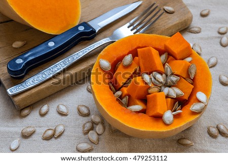Sliced raw orange Pumpkin. Knife and fork on a wooden cutting board. Concept - healthy food.