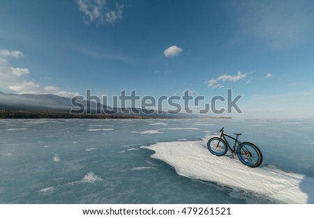 Fatbike (also called fat bike or fat-tire bike) - Cycling on large wheels. Bicycling is at sunset on the ice.