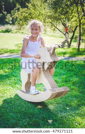 Small girl on toy unicorn  in park.