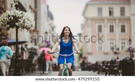 Joyful girl is riding a bike on the street Royalty-Free Stock Photo #479299150