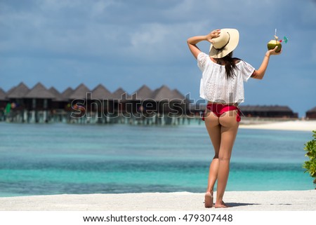 Close up girl back in bikini against ocean beach and cocktail
