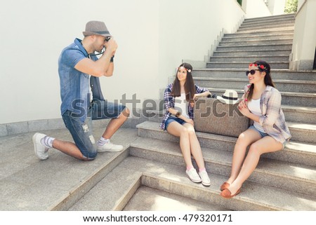 Young hipster man taking a photo of two young old-fashioned girl with an vintage camera.
