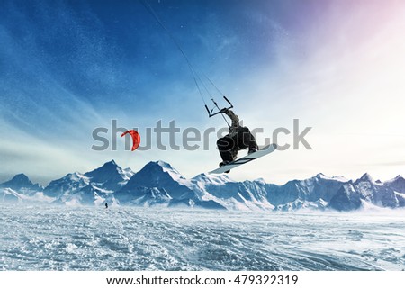 Young men, ride snowboarding on frozen lake in the mountains, in the rays of the rising sun, in winter, on vacation Royalty-Free Stock Photo #479322319