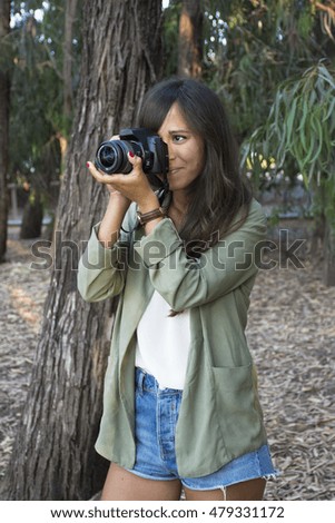 Cute girl taking a picture using SLR camera outdoors