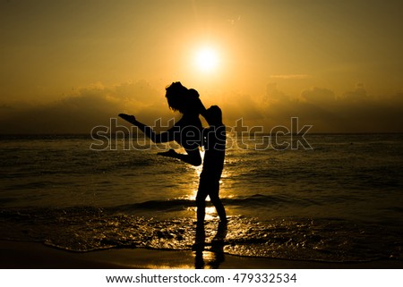 Shape of romantic young couple dancing at the sunset at the seashore. Silhouettes of romantic couple dancing at the sunset. Romantic, togetherness and happiness concept. Vacation and holiday concept. 
