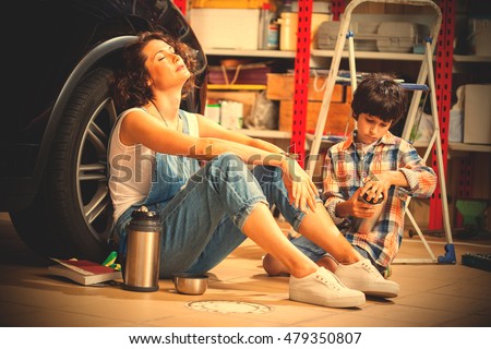 resting mechanic woman and boy with thermos in an auto repair workshop. instagram image filter retro style