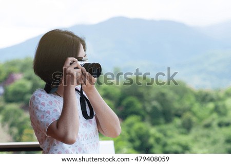 Happiness of young Asian woman holding camera and taking mountains landscape photo. copy space.