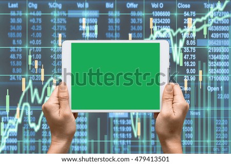 Female hand holding tablet touch screen showing green screen background for insert text and picture over the Stock market exchange data on LED display,Business financial and technology concept