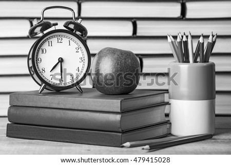 Back to school, school books with apple on desk. Old style, black - white photo.