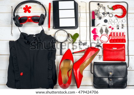 Women clothing set and accessories on white wooden background. Red and black. Top view,