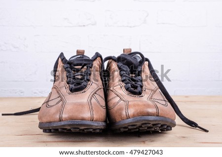 pair of brown leather shoes  on  wooden floor White brick wall background