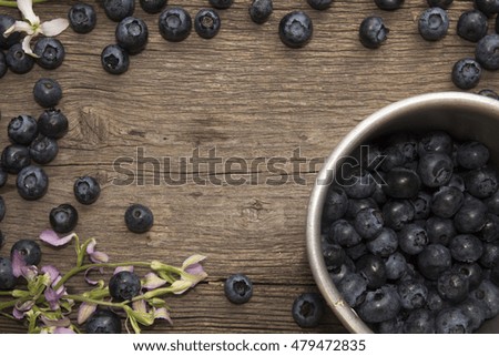 Bilberry and aluminum mug filled blueberries on rustic table
