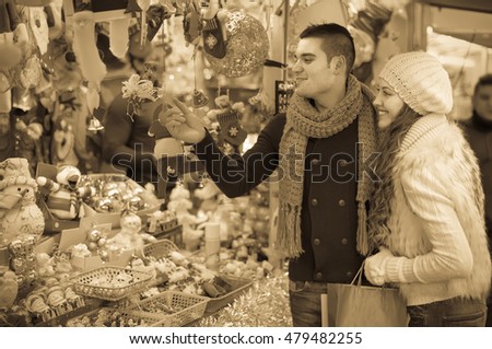 Positive young man with beautiful girlfriend at counter of X-mas market. Shallow focus