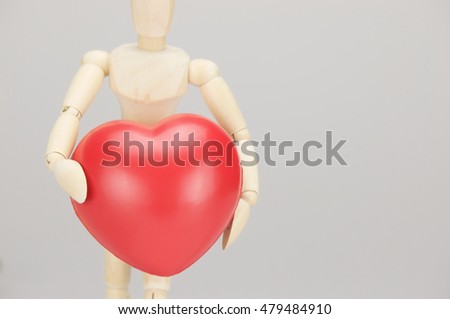Wooden dummy holding red heart on left with white background and copy space. Healthcare and medical concepts photography.
