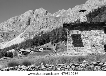 Savoie, France. Traditional stone houses with solar panels (modern approach to sustainability issue). Wooden Statue of bear with Savoie flag emblem. Vanoise National Park at French Alps. 