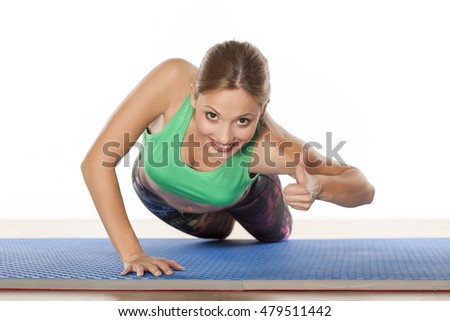 young beautiful woman doing push-ups and showing thumbs up