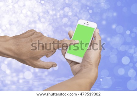 Person using smartphone green screen holder on hand with blurry background bokeh 