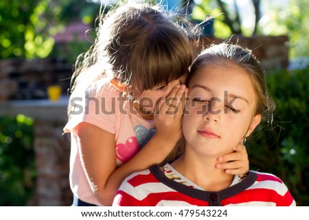 Two little girls telling secrets