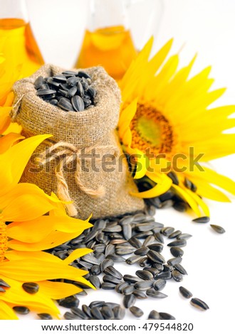 Small bag with sunflower seeds on a background of flowers and a bottle of sunflower oil