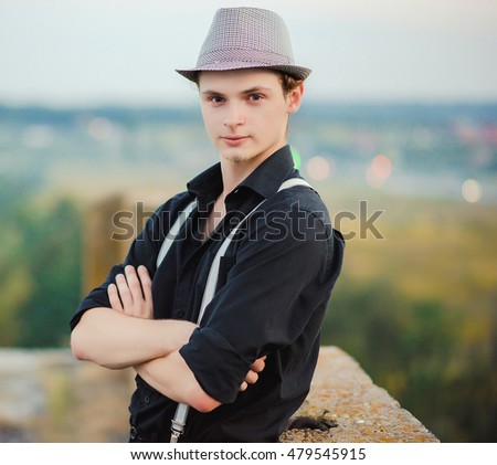 Young dancer in dark clothes posing on the roof.Young stylish boy in casual style posing on the roof.Photo stylized film with characteristic noise