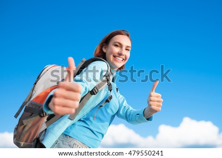 happy woman mountain hiker show thumb up and take a selfie with blue sky and white clouds, caucasian