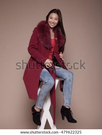 Winter Woman in Luxury Fur Coat. Fashion asian model om beige background.