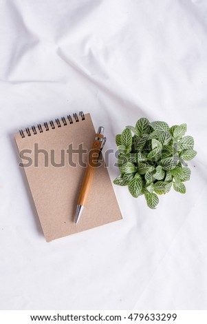 small plant pot with note book paper and wood pencil on white ba