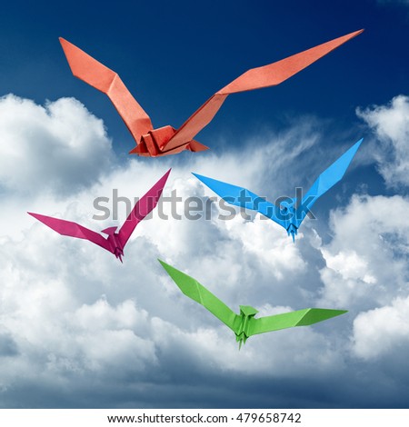 Group of flying birds in Origami with cloudy blue sky, there is a path for each bird.