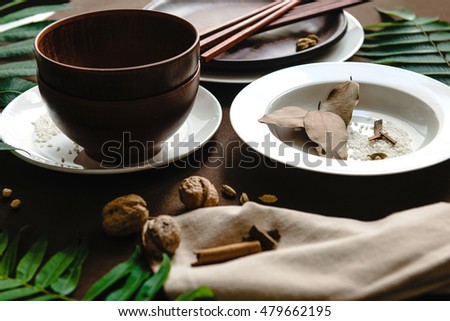 Set of japanese tableware. Black, white ceramic plates, brown bowls, wooden spoons and chopsticks on black background. Japanese serving style