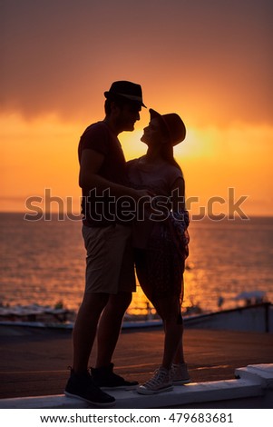 Silhouette couple standing over sunset background. Romantic atmosphere. Stylish clothes. Summer time together.